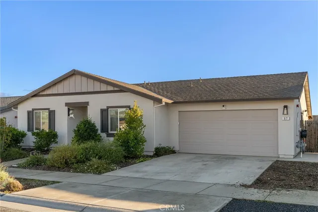 a front view of a house with garage and plants