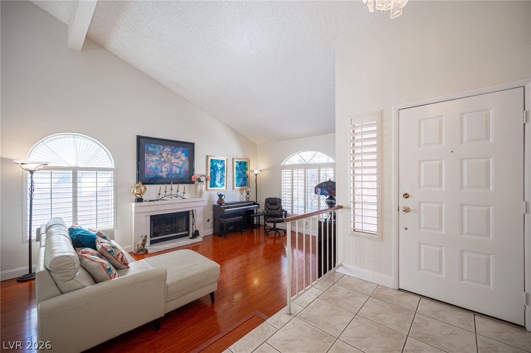 718 Rusty Spur Drive Henderson, NV 89014 - Photo 4 of 50 Step into a sun-filled living space featuring high ceilings, a cozy fireplace, and gleaming hardwood floors.