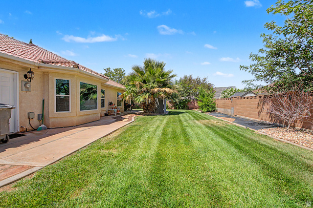 3034 Swiss Drive Santa Clara, UT 84765 - Photo 40 of 59 Spacious rear yard featuring an expansive lawn, concrete patio, mature landscaping, and a privacy wall