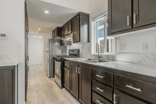 a kitchen with stainless steel appliances granite countertop a sink stove and refrigerator