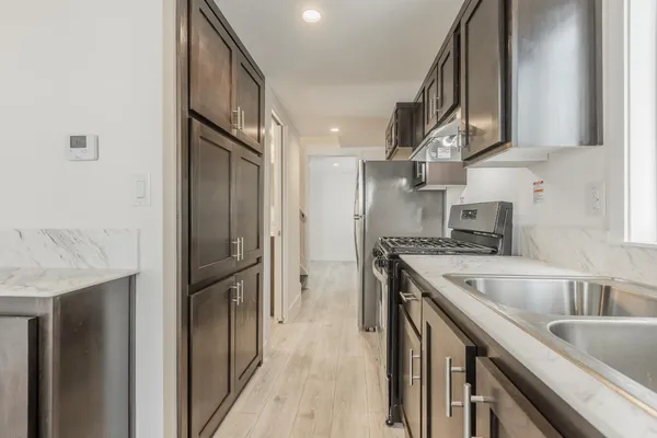 a kitchen with stainless steel appliances granite countertop a refrigerator a sink and a stove