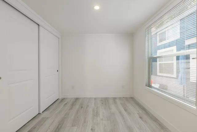 a view of an empty room with wooden floor and a window