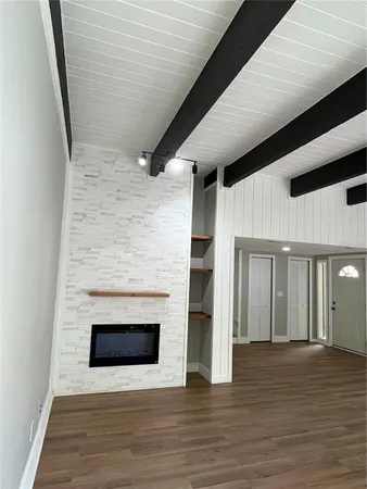 a view of an empty room with wooden floor and a fireplace