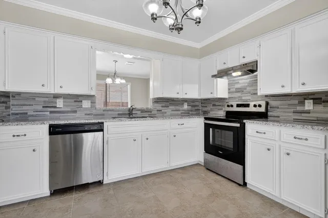 a kitchen with granite countertop white cabinets white stainless steel appliances with a sink and dishwasher