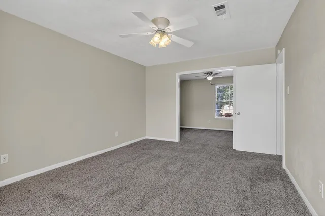 an empty room with closet and a ceiling fan