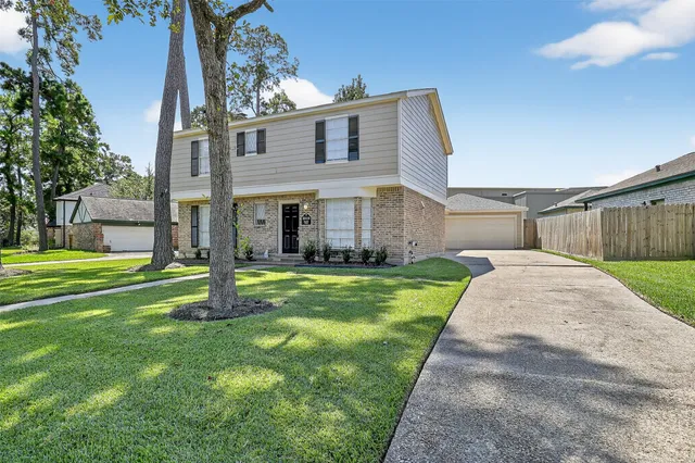 a view of a house with a yard and large tree