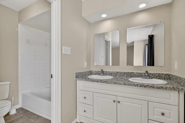 a bathroom with a granite countertop sink double mirror and bathtub