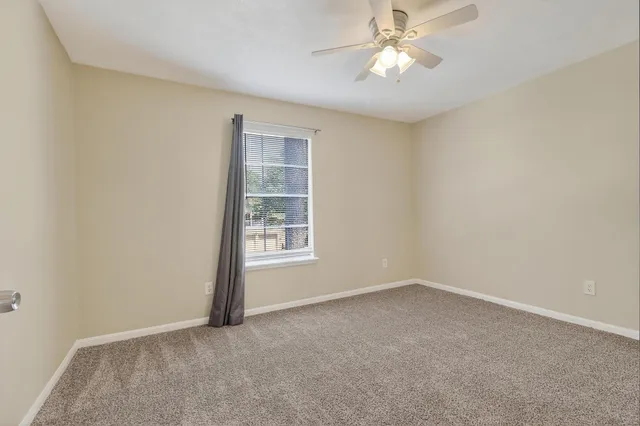 an empty room with a chandelier fan and windows