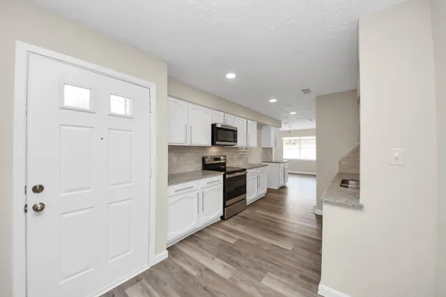 a large kitchen with cabinets wooden floor and stainless steel appliances