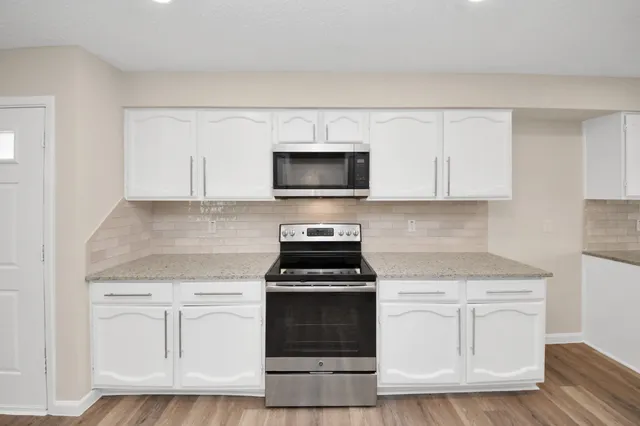 a kitchen with white cabinets and black appliances
