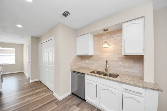 a kitchen with granite countertop white cabinets and a sink
