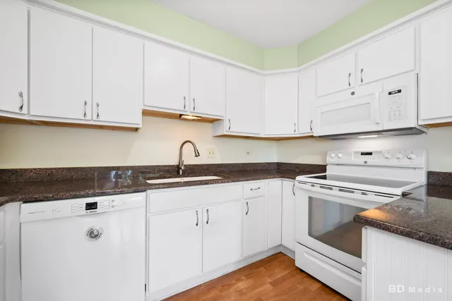 a kitchen with granite countertop white cabinets and white appliances