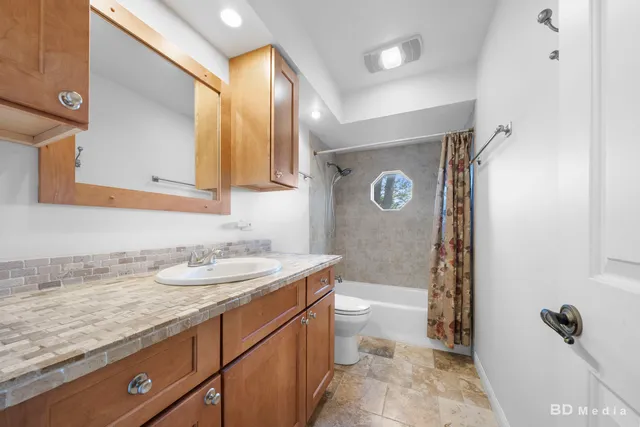 a bathroom with a granite countertop sink a mirror a toilet and bathtub