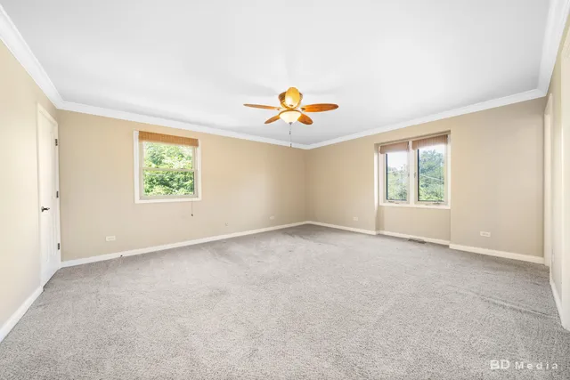 an empty room with windows and a ceiling fan