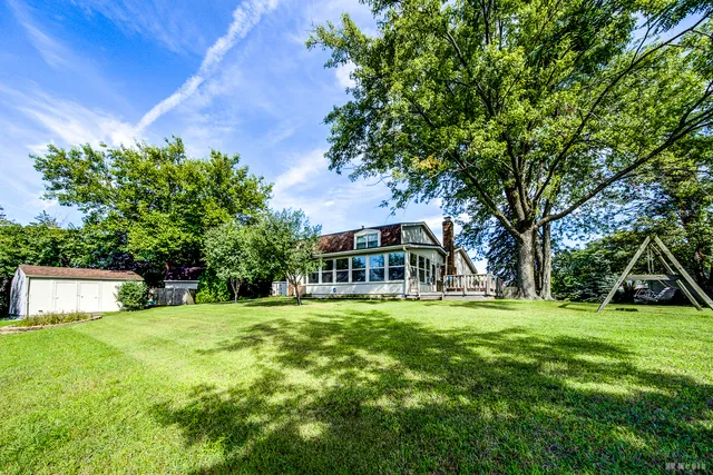a view of a house with a big yard and large trees