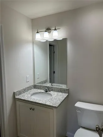 a bathroom with a granite countertop sink and a toilet