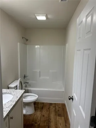 a bathroom with a granite countertop sink a toilet and shower