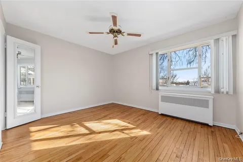 a view of an empty room with a window and wooden floor