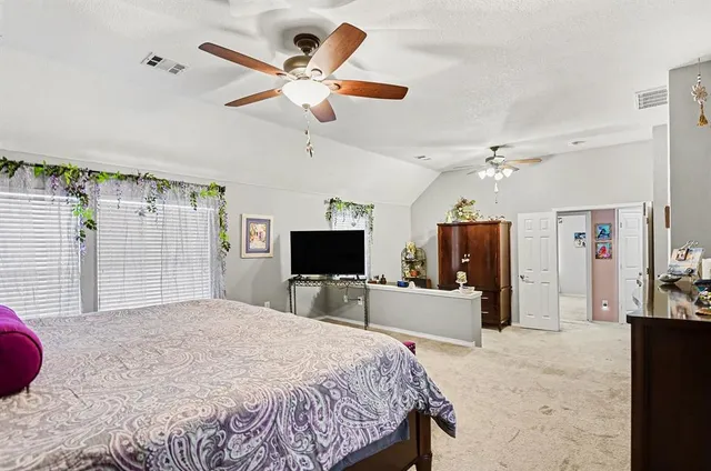 a bedroom with a bed a flat screen tv and a chandelier