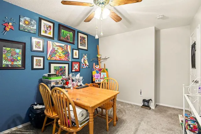 a dining room with furniture and a chandelier fan