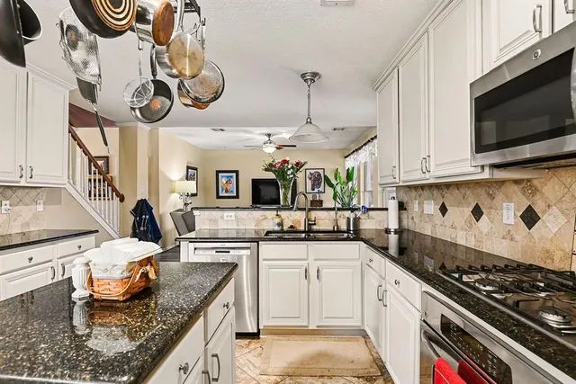 a kitchen with stainless steel appliances granite countertop a stove a sink and a microwave