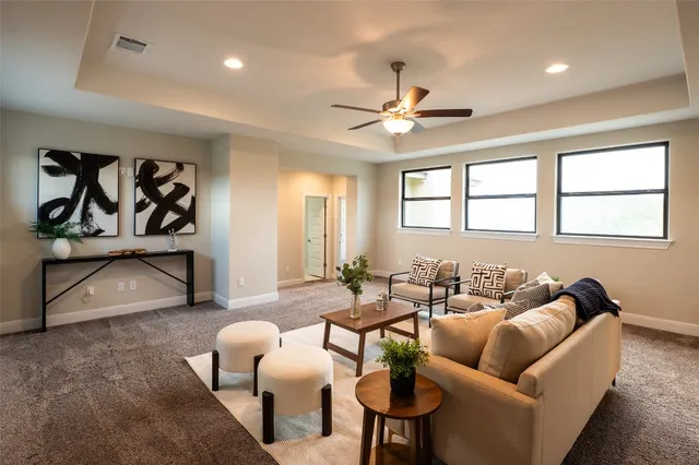 a living room with furniture ceiling fan and a large window