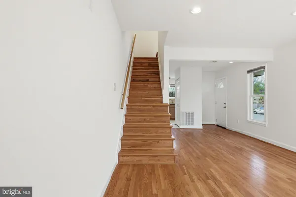 a view of a hallway with stairs and wooden floor