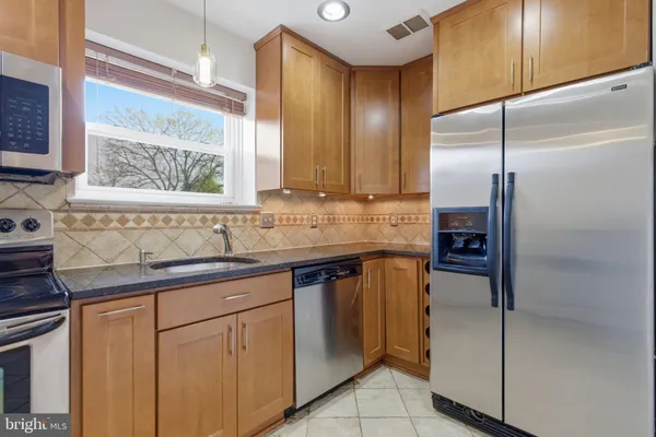 a kitchen with stainless steel appliances granite countertop a sink and a refrigerator