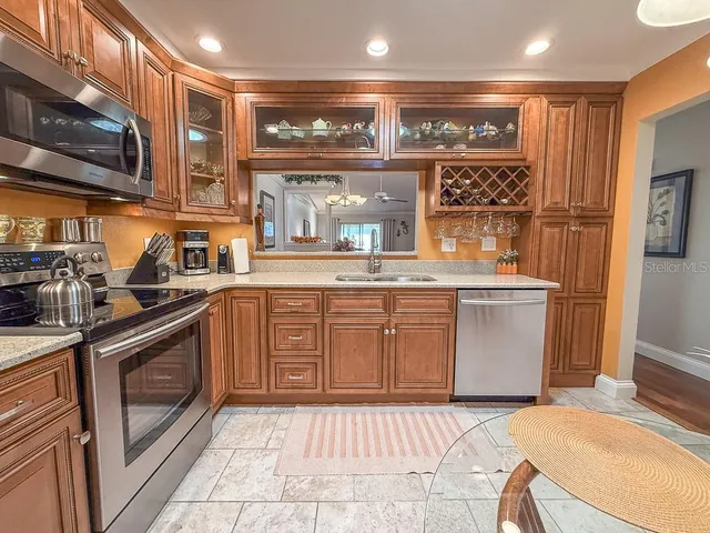 a kitchen with stainless steel appliances granite countertop a sink and dishwasher a refrigerator with wooden cabinets