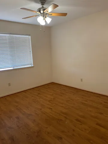 an empty room with a window and ceiling fan