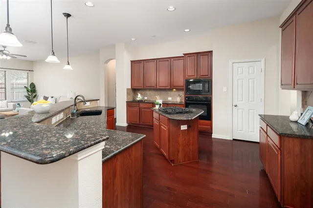 a kitchen with stainless steel appliances granite countertop a sink a stove and a wooden floors