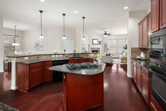 a kitchen with stainless steel appliances granite countertop a sink a stove and a wooden floors