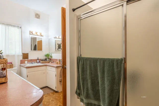 a bathroom with a granite countertop sink a mirror and shower
