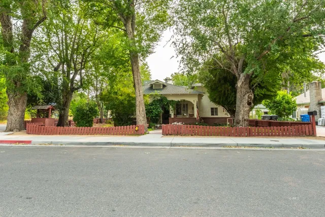 a front view of a house with a yard and a large tree