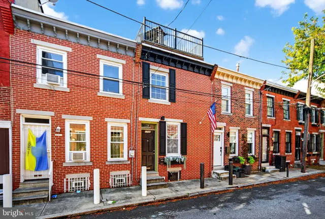 a roof deck with couches and potted plants with wooden floor