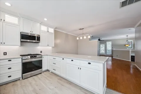 a kitchen with granite countertop white cabinets and stainless steel appliances