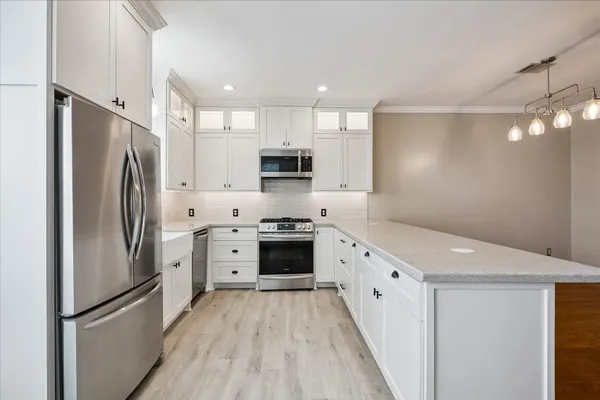 a kitchen with white cabinets stainless steel appliances and a refrigerator