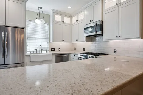 a kitchen with stainless steel appliances granite countertop a sink a stove and a refrigerator
