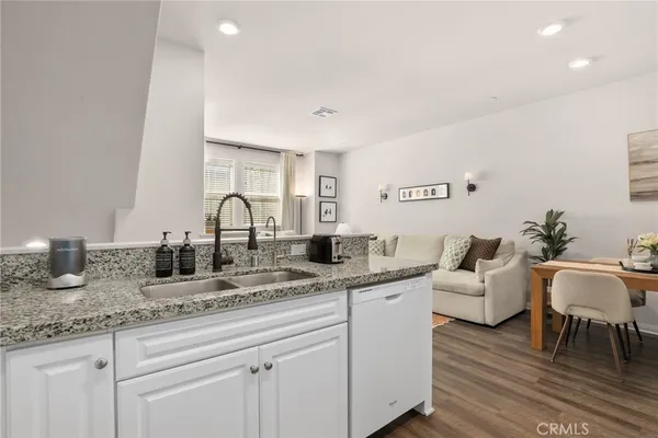 a kitchen with granite countertop a sink and white cabinets