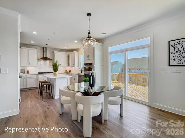 a kitchen with granite countertop a refrigerator a stove a dining table and chairs with wooden floor