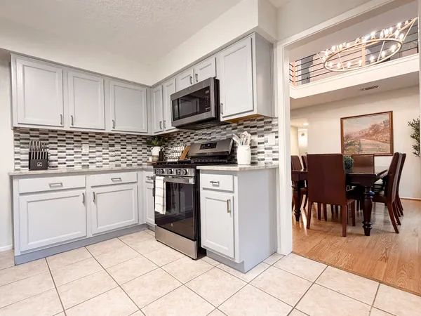 a kitchen with stainless steel appliances granite countertop a stove a sink a dining table and chairs