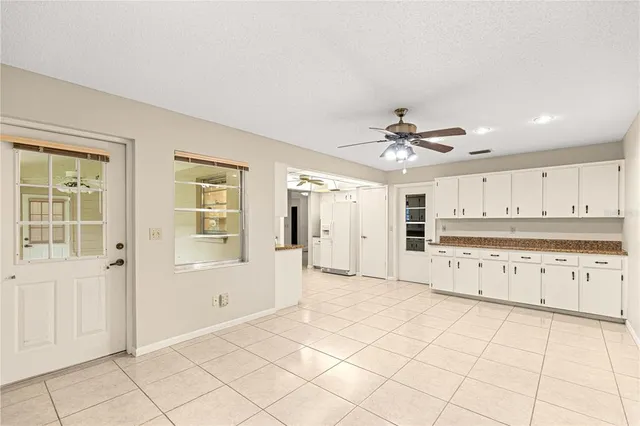 a view of a kitchen with cabinet a chandelier fan and windows