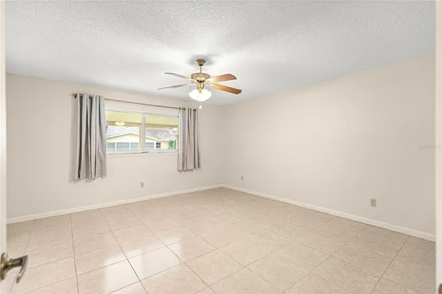 an empty room with windows and chandelier fan