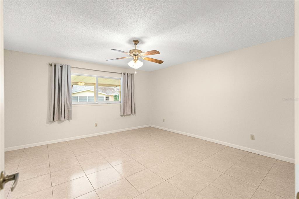 8665 Southwest 94 Street, Unit C Ocala, FL 34481 - Photo 20 of 29 an empty room with windows and chandelier fan