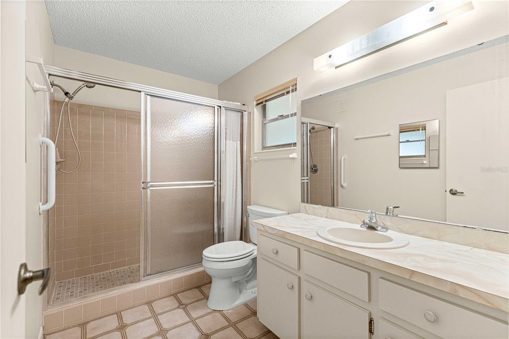 8665 Southwest 94 Street, Unit C Ocala, FL 34481 - Photo 23 of 29 a bathroom with a granite countertop sink toilet and shower