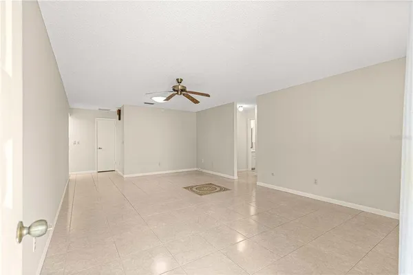 an empty room with a chandelier fan and windows