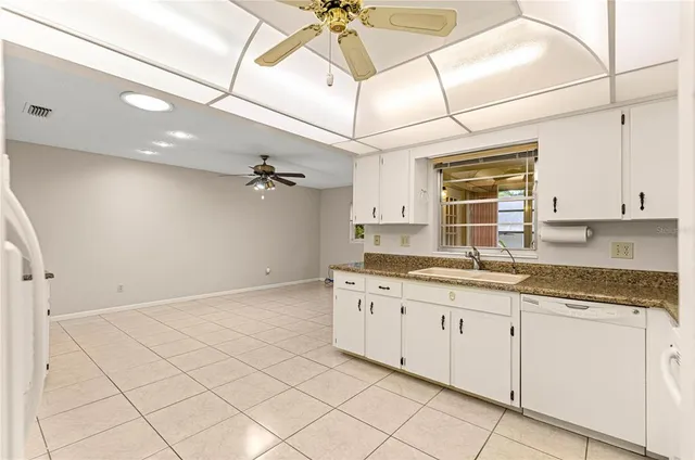 a kitchen with granite countertop white cabinets white appliances and a sink