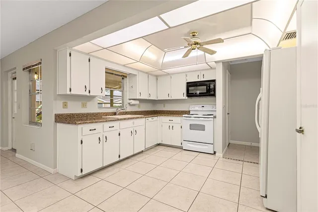 a kitchen with granite countertop white cabinets and white appliances