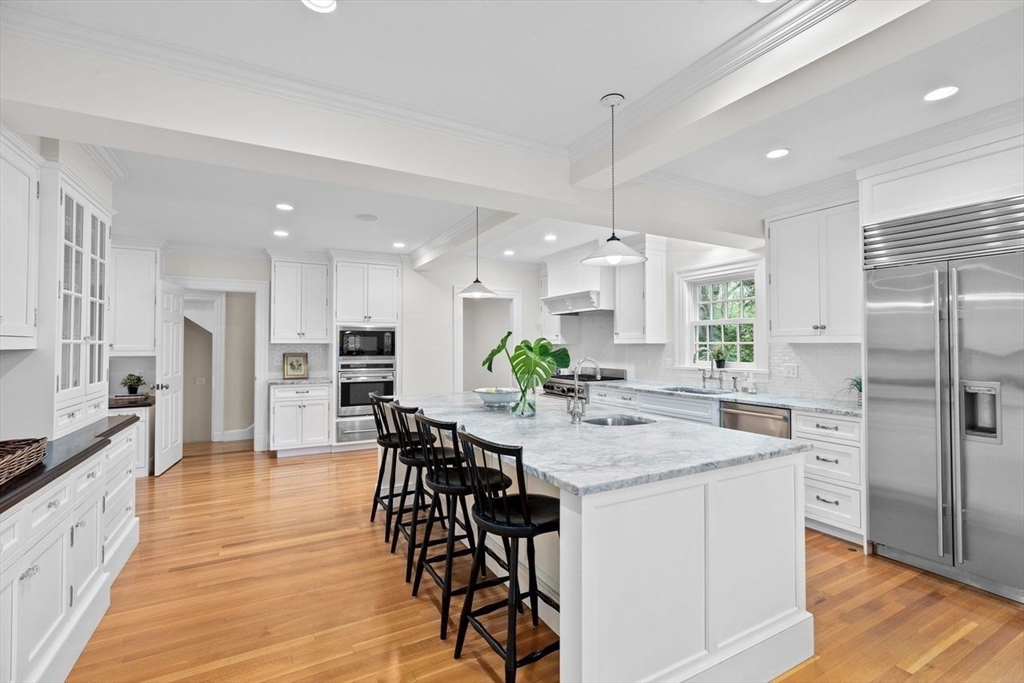 44 Montvale Road Newton, MA 02459 - Photo 6 of 37 a kitchen with stainless steel appliances kitchen island granite countertop a dining table chairs stove refrigerator and cabinets