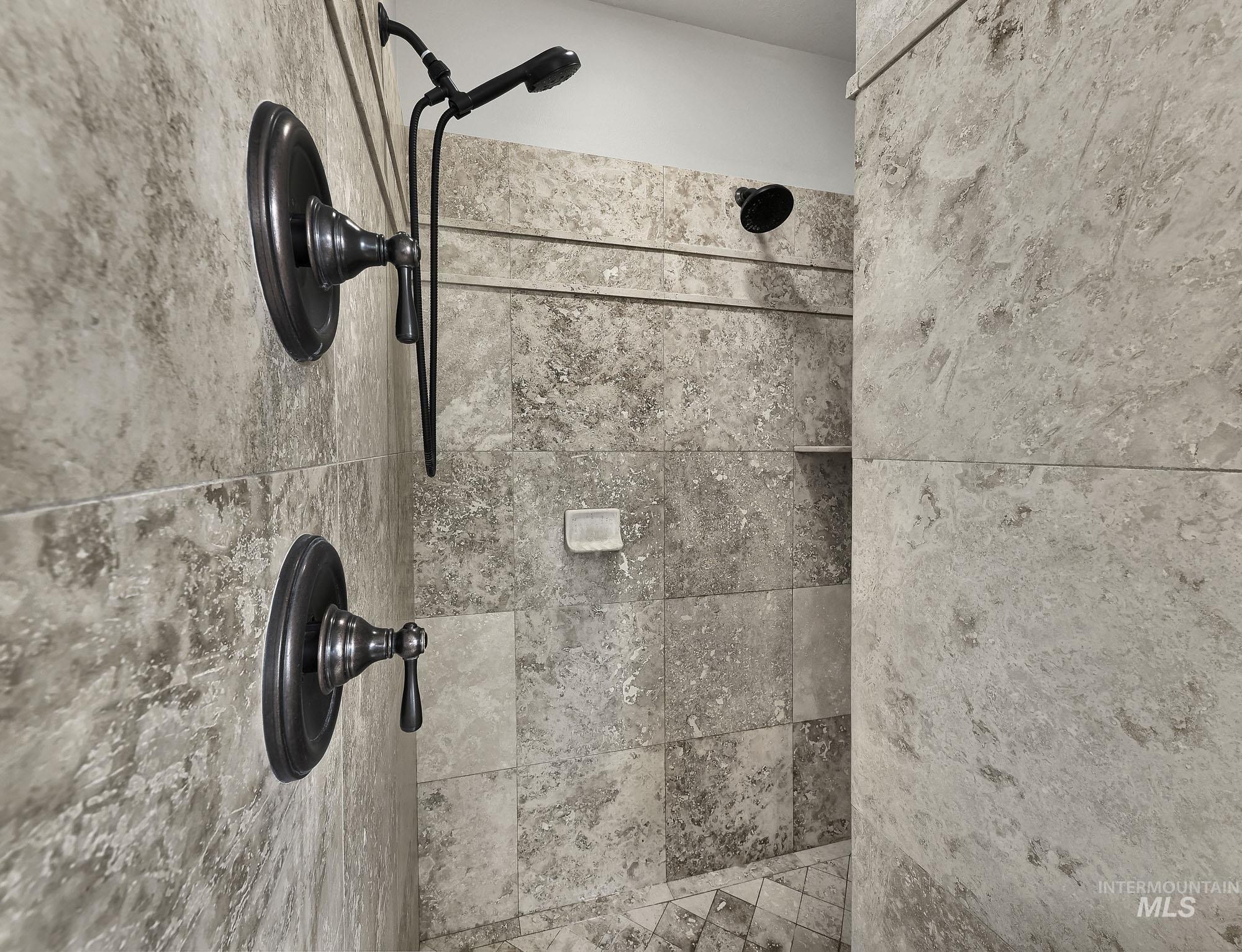 2172 West Cedar Grove Street Meridian, ID 83646 - Photo 17 of 49 Shower with full-height stone-finish tile, oil-rubbed bronze fixtures, a handheld showerhead, and a built-in shower niche